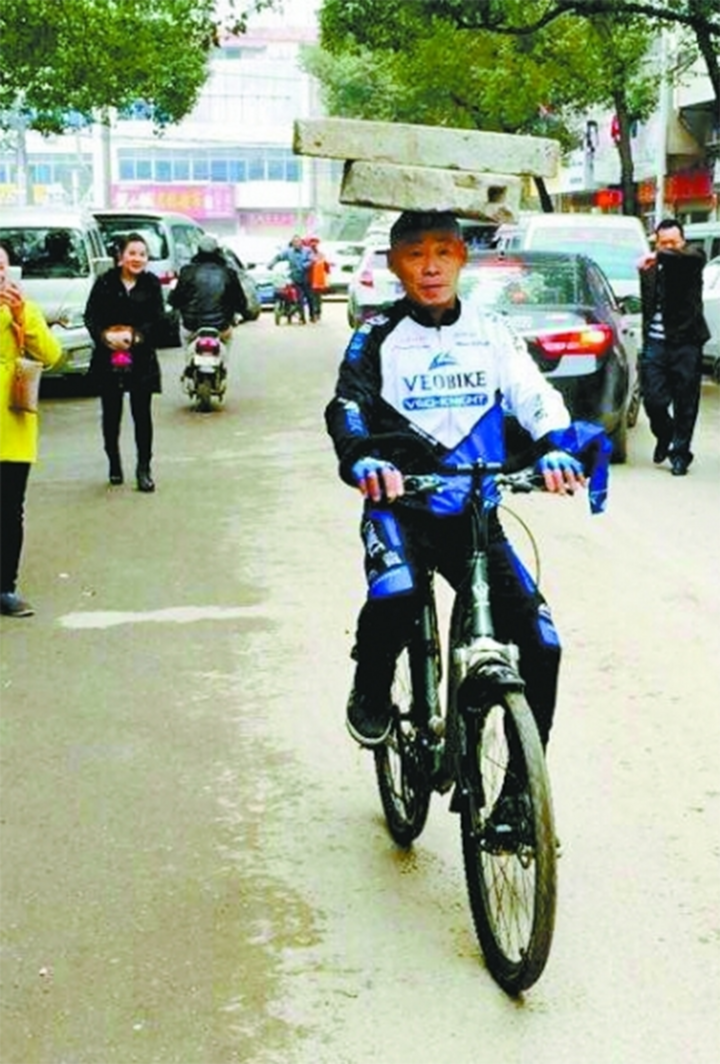 Ông Trương Huân Mộc vừa đội cối đá trên đầu, vừa đạp xe